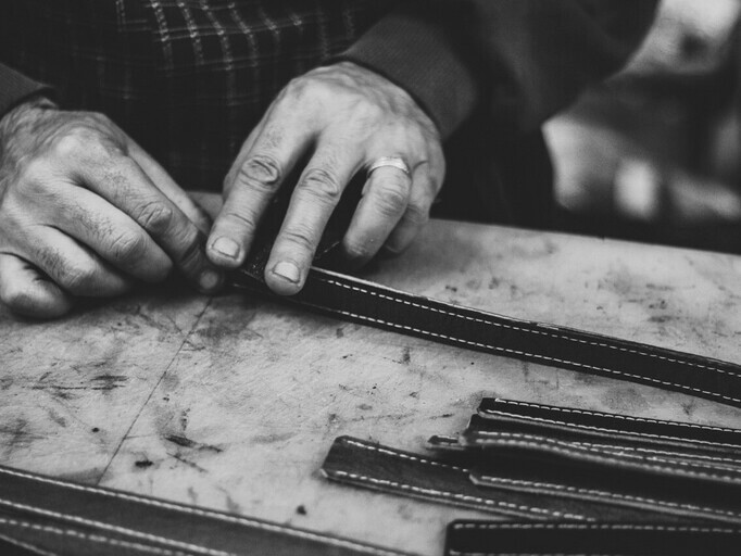 Photo en noir et blanc d’un maître artisan travaillant le cuir dans son atelier